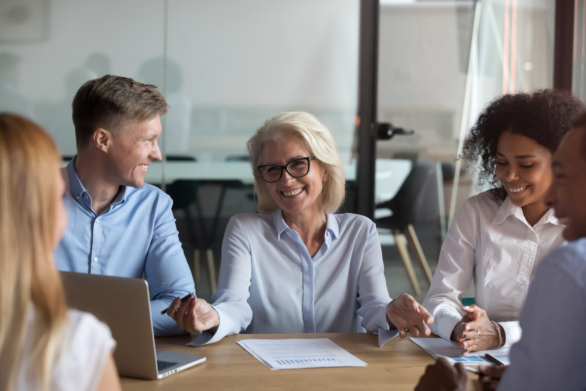 Different people young and aged multinational employees sitting around table